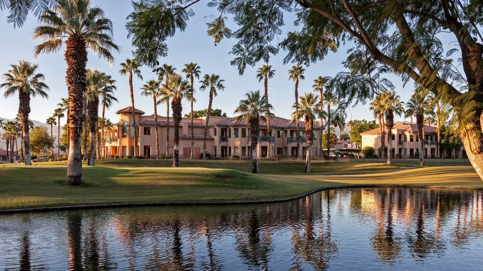 Palm trees and resort-style apartments beside a small lake at sunset, illustrating whether timeshares are worth buying