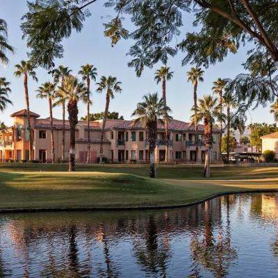 Palm trees and resort-style apartments beside a small lake at sunset, illustrating whether timeshares are worth buying